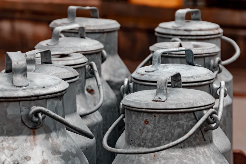 Des bidons en métal gris empilés, utilisés pour stocker des ingrédients de lessive maison.