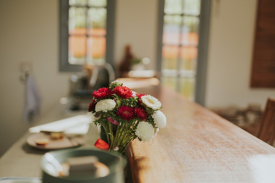 Un bouquet de fleurs colorées posé sur un comptoir en bois dans une cuisine lumineuse.