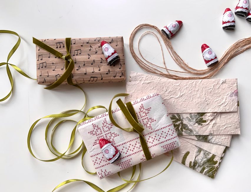 Cadeaux écoresponsables joliment emballés avec des rubans et des décorations festives sur un fond blanc.